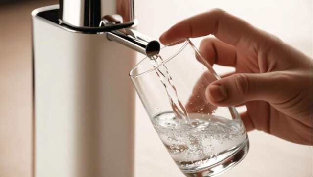家庭用浄水器から新鮮な水をグラスに注ぐ様子